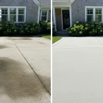 A high-contrast before and after shot of a concrete driveway. The left side is covered in dark algae and oil stains, while the right side is bright, clean, and pristine. A modern suburban home is visible in the background