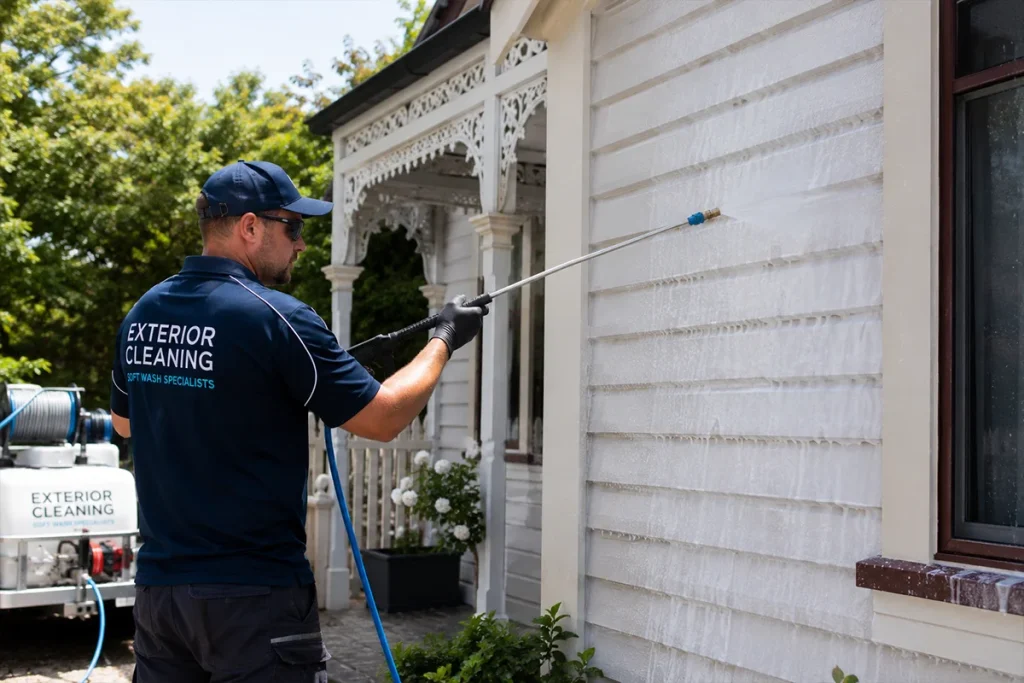 Soft wash technician applying biodegradable solution to Victorian painted cottage exterior Martha's Vineyard